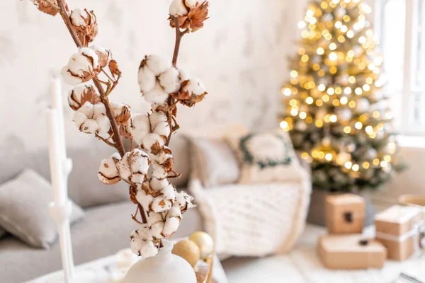 Florero con ramas de algodón. Salón luminoso con árbol de Navidad. Sofá cómodo, ventanas grandes altas —  Fotos de Stock