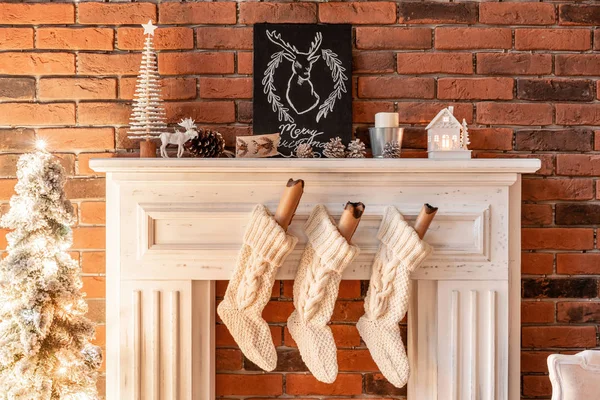 Weiße Wollsocken für den Weihnachtsmann auf dem Kamin. Dachgeschosswohnungen, Backsteinmauer mit Kerzen und Christbaumkranz. — Stockfoto