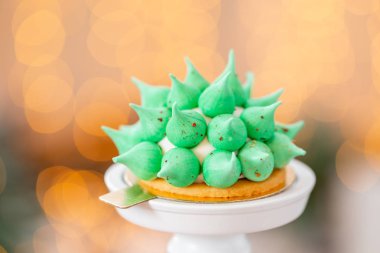 Mini mus pasta tatlı yeşil beze ile. Garland lambalar bokeh arka plan. Modern Avrupa pasta. Fransız mutfağı. Noel Tema