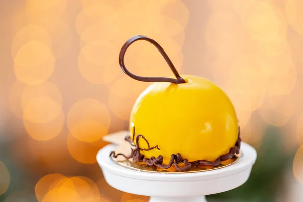Mini mousse bakverk dessert med gul glaserat på garland lampor bokeh bakgrund. Moderna europeiska tårta. Franska rätter. Jultema — Stockfoto