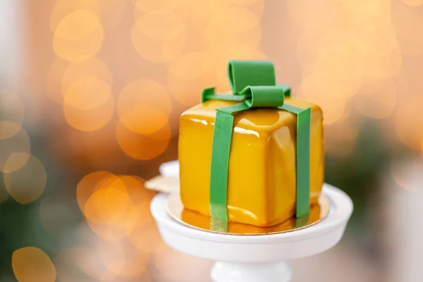 Μίνι μους σοκολάτας με κίτρινο τζάμια. Γιρλάντα λαμπτήρες bokeh φόντο. Με τη μορφή δώρου, κορδέλες της σοκολάτας. Σύγχρονη Ευρωπαϊκή κέικ. Γαλλική κουζίνα. Θέμα Χριστουγέννων — Φωτογραφία Αρχείου