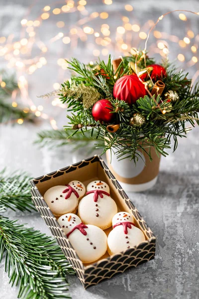 Verschiedene süße Makronen im Karton. Keks in Form eines Schneemanns. Tannenzweige auf grauem Hintergrund. Frohe Weihnachten. Neujahrsstimmung — Stockfoto
