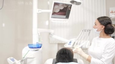 Diş hekimi makro fotoğraf makinesi ağız boşluğu hastanın ile inceliyor. Genç Afro-Amerikan erkek hasta sandalyeye diş kliniği. Tıp, sağlık, stomatology kavramı.