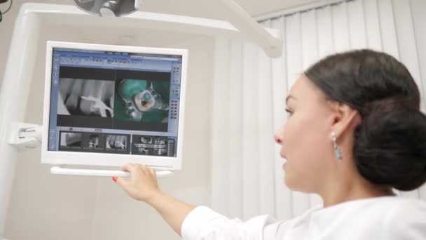 El dentista muestra una imagen de la radiografía en el monitor para el paciente Joven afroamericano paciente en silla en la clínica dental. Medicina, salud, concepto de estomatología . — Vídeo de stock
