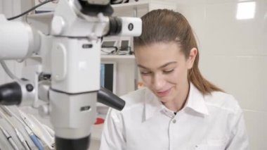 Diş hekimi hastaya modern mikroskop yönlendirir. Güzel bir kadın doktor diş hekimi. Genç Afro-Amerikan erkek hasta sandalyeye diş kliniği. Tıp, sağlık, stomatology kavramı.