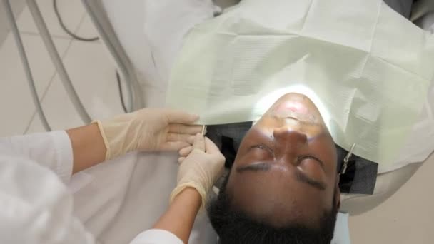 La mujer dentista trata a la paciente. Joven paciente afroamericano en silla en la clínica dental. Medicina, salud, concepto de estomatología . — Vídeo de stock