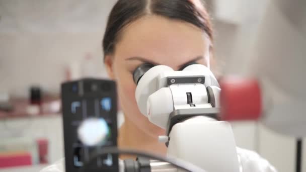 La doctora dentista usa un microscopio. Medicina, salud, concepto estomatológico. dentista realiza inspección y concluye. — Vídeo de stock