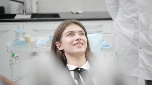 Retrato de uma jovem menina bonita na cadeira de dentista na clínica odontológica. Medicina, saúde, conceito de estomatologia. dentista a tratar um paciente. Mulher sorrindo — Vídeo de Stock