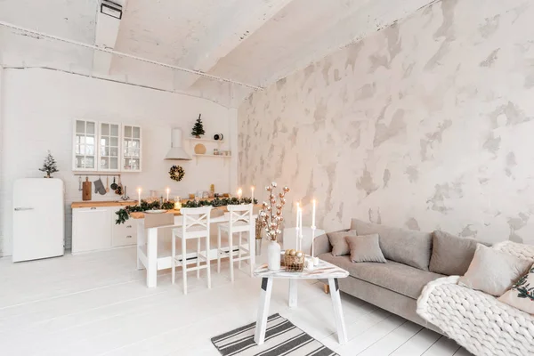 Loft stil lägenhet, stort rymligt vardagsrum med matbord och kök. Rum med julgran. Bekväm soffa, hög stora fönster. Ljus vit tegelvägg. — Stockfoto