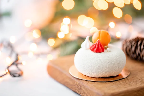 Mini-Moussegebäck Dessert mit weißem Velours auf Girlanden Lampen Bokeh Hintergrund bedeckt. moderner europäischer Kuchen. Französische Küche. Weihnachtsthema — Stockfoto