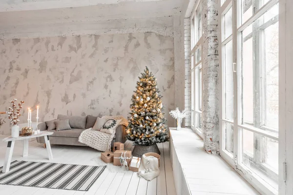 Helles Wohnzimmer mit Weihnachtsbaum. bequemes Sofa, hohe große Fenster. helle weiße Ziegelmauer. — Stockfoto