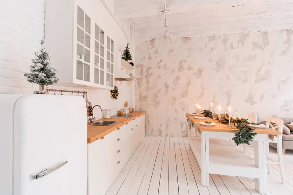 Loft stil lägenhet, stort rymligt vardagsrum med matbord och kök. Rum med julgran. Ljus vit tegelvägg. — Stockfoto