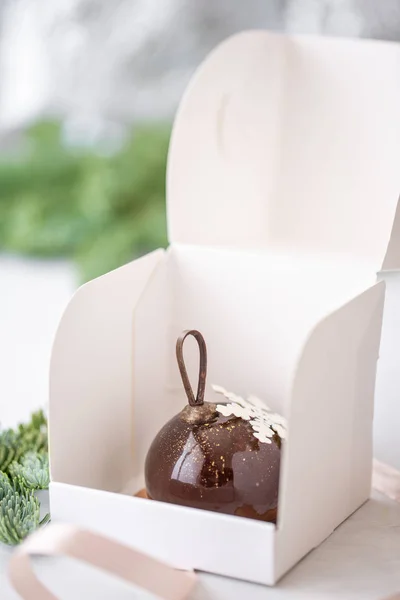 Mini mus pasta tatlı çikolata ile tek tek sarılı beyaz kutusunda sırlı. Ladin bokeh arka plan üzerinde dalları. Modern Avrupa pasta. Fransız mutfağı. Noel. Kar tanesi — Stok fotoğraf