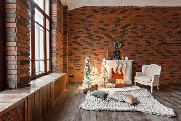 Loft apartments, tegelvägg med ljus och julgran krans. Vit ull strumpor för Santa på spisen. Stickade matta och stol, julgran — Stockfoto