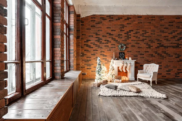Loft apartments, brick wall with candles and Christmas tree wreath. White wool socks for Santa on the fireplace. Knitted carpet and chair, Christmas tree — Stock Photo, Image