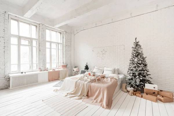 Dimineața de Crăciun, Micul dejun în pat, cafea și deserturi. Apartamente în stil Loft. Pat în dormitor, ferestre mari. Zid de cărămidă cu lumânări şi pom de Crăciun. Culoare albă . — Fotografie, imagine de stoc