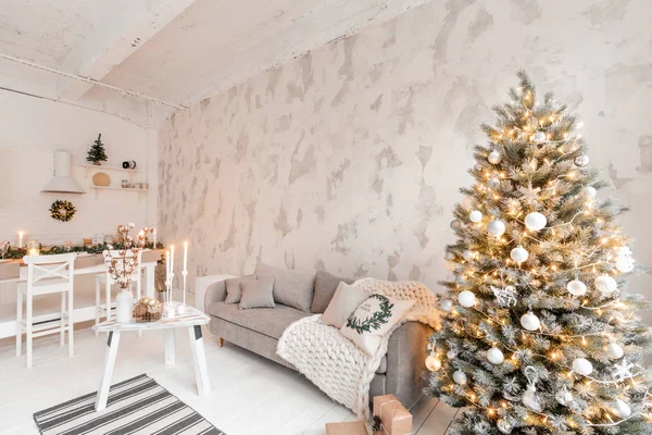 Loft stil lägenhet, stort rymligt vardagsrum med matbord och kök. Rum med julgran. Bekväm soffa, hög stora fönster. Ljus vit tegelvägg. — Stockfoto