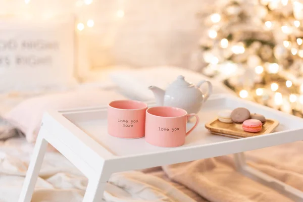 Frukost på sängen, bricka med kopp kaffe och macaroon. Moderna sovrum inredning. Romantisk morgon överraskning. — Stockfoto