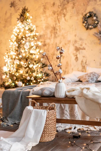 Vase mit Baumwollzweigen vorhanden. Wohnungen im Loft-Stil, Weihnachtsbaum. Bett im Schlafzimmer, hohe große Fenster — Stockfoto