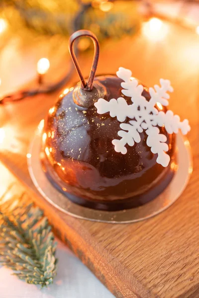 Mini-Moussegebäck-Dessert mit Schokolade glasiert. Girlandenlampen bokeh auf dem Hintergrund. moderner europäischer Kuchen. Französische Küche. Weihnachtsthema. Schneeflocke — Stockfoto