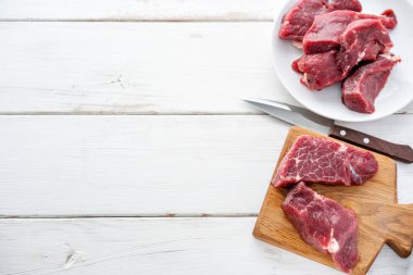 Çiğ et. Ham taze Dana biftek bir tahta Ahşap kesme ve oyma bıçağı. Beyaz ahşap arka plan, üstten görünüm, kopya alanı, gün ışığından yararlanma