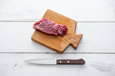 Çiğ et. Ham taze Dana biftek bir tahta Ahşap kesme ve oyma bıçağı. Beyaz ahşap arka plan, üstten görünüm, kopya alanı, gün ışığından yararlanma