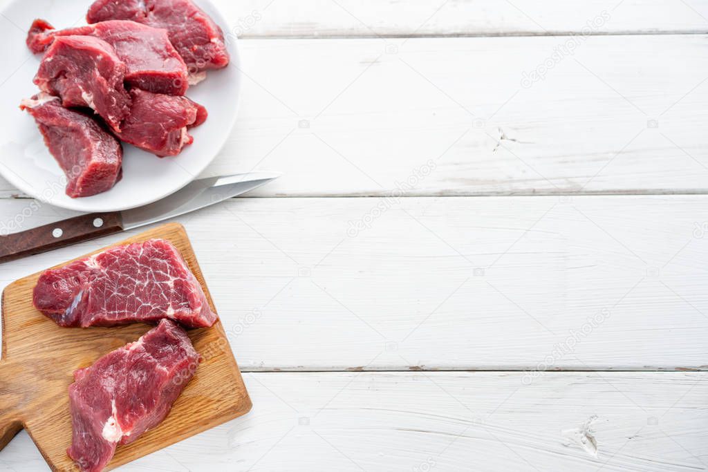 Raw meat. Raw fresh beef steak on a wood cutting board and Carving knife. White wooden background, top view, copy space, Daylight