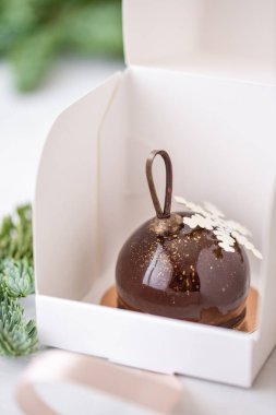 Mini mus pasta tatlı çikolata ile tek tek sarılı beyaz kutusunda sırlı. Ladin bokeh arka plan üzerinde dalları. Modern Avrupa pasta. Fransız mutfağı. Noel. Kar tanesi