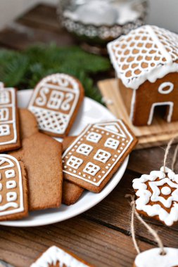 Bir sürü beyaz tabakta Avrupa evler şeklinde zencefilli bisküvi. Beyaz tatlı sır ile dekore edilmiştir. Noel ruh hali, kış sabahı.