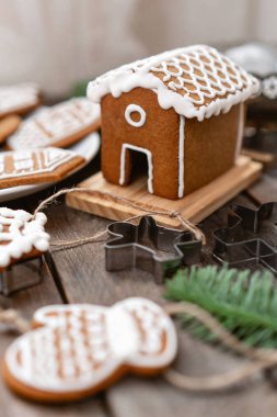 Bir sürü farklı formunda kahverengi ahşap masa, zencefilli bisküvi. Beyaz tatlı sır ile dekore edilmiştir. Noel ruh hali, kış sabahı. Çam dalları ve pişirme için formları