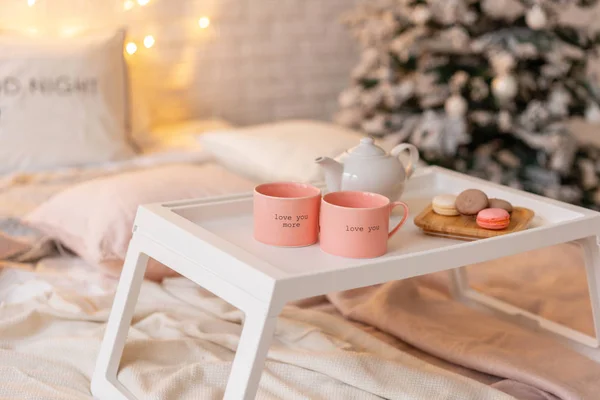 Desayuno en la cama, bandeja con taza de café y macarrón. Interior del dormitorio moderno. Sorpresa romántica de mañana . — Foto de Stock