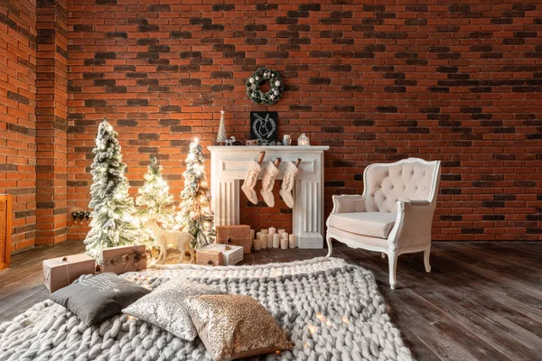 Чердачные квартиры, кирпичная стена со свечами и елочным венком. Белые шерстяные носки для Санты на камине. Трикотаж и стул, Рождественская елка — стоковое фото