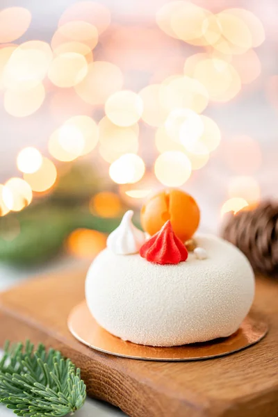 Mini-Moussegebäck Dessert mit weißem Velours auf Girlanden Lampen Bokeh Hintergrund bedeckt. moderner europäischer Kuchen. Französische Küche. Weihnachtsthema — Stockfoto