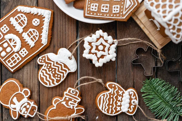 Bir sürü farklı formunda kahverengi ahşap masa, zencefilli bisküvi. Beyaz tatlı sır ile dekore edilmiştir. Noel ruh hali, kış sabahı. Çam dalları ve pişirme için formları