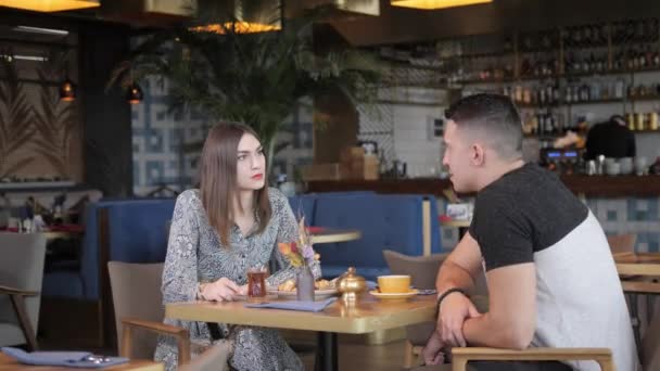 Mujer bonita y hombre deportivo tomando café y relajarse en la cafetería de estilo oriental. Desayuno, agradable mañana, el comienzo de la jornada laboral — Vídeo de stock