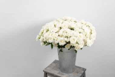 Ahşap masa üzerinde büyük lüks parlak buket. Bahçe sprey gül beyaz renk. buket metal vazo içinde