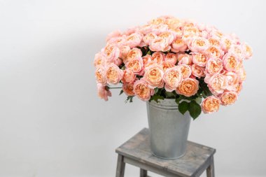 Büyük lüks parlak buket şakayık ahşap masanın üzerine yükseldi. Bahçe sprey gül pembe ve şeftali rengi. buket metal vazo içinde