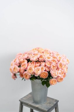 Büyük lüks parlak buket şakayık ahşap masanın üzerine yükseldi. Bahçe sprey gül pembe ve şeftali rengi. buket metal vazo içinde