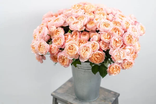 Big luxury bright bouquet peony rose on wooden table. Garden spray roses of pink and peach color . bouquet in metal vase
