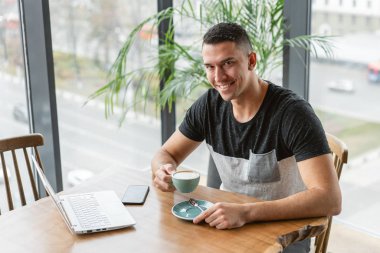 Genç adam bir fincandan kahve içme. Freelancer iş modern coworking netbook üzerinde. Programcı uzak iş. Başarılı insanlar, işadamı rahat kafede. Yüksek büyük pencereler