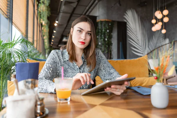 Young woman Typing on tablet, chatting, maintains a blog. Freelancer work in cafe modern coworking. Successful people, businessman in comfortable cafe . High large Windows — Stock Photo, Image