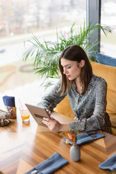 Young woman Typing on tablet, chatting, maintains a blog. Freelancer work in cafe modern coworking. Successful people, businessman in comfortable cafe . High large Windows — Stock Photo, Image