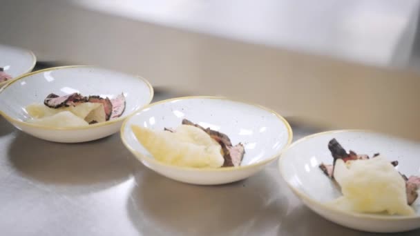 Gros plan Ligne de assiettes plats. Chefs de groupe occupés dans la cuisine commerciale du restaurant gastronomique. Le personnel d'un restaurant ou d'une cuisine d'hôtel cuisine délicieux, ils décorent les plats — Video