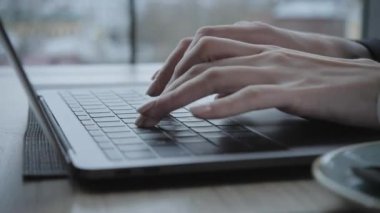 Genç kadın kahve oturuşta alışveriş tahta masada. Tablo üzerinde gri alüminyum dizüstü bilgisayardır. Kız bloglama, internet tarama, sohbet