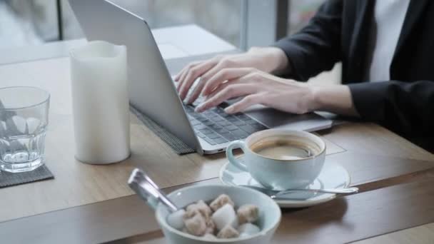 Giovane donna seduta in caffetteria al tavolo di legno. Sul tavolo è computer portatile in alluminio grigio. Ragazza blogging, navigazione internet, chat — Video Stock