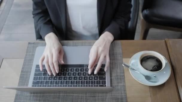Uroczy młoda kobieta siedząc w kawiarni. Na stole jest szary aluminium laptopa. Dziewczyna blogów, przeglądania Internetu, rozmowy w sieciach społecznościowych. Używa połączenia bezprzewodowego Internetu — Wideo stockowe