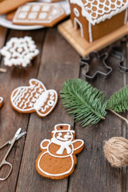 Kardan adam Noel kış sabahı şeklinde kurabiyeler. Kadın bal gingerbread çerezleri üzerinde buzlanma çizer. Ahşap kahverengi masa. kopya alanı.