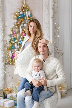 Genç Anne aptal ve küçük oğlu ile oynamak. Mutlu bir aile evde eğleniyor. Noel sabahı parlak oturma odasında. Baba, hamile anne ve bebek oğulları. Yeni Yılınız Kutlu Olsun. Baş aşağı