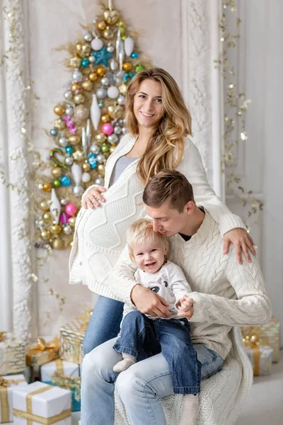 Young parents fool around and play with little son. Happy family having fun at home. Christmas morning in bright living room. Father, pregnant mother and their baby boy. Happy new year. Upside down