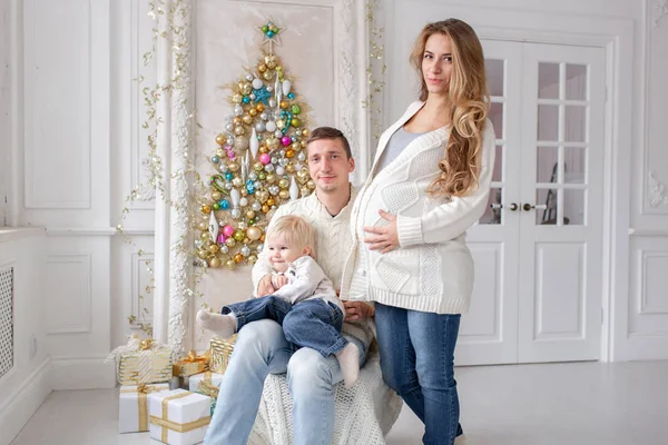 Šťastná rodina portrét v Home - otec, těhotné matky a jejich malého syna. Šťastný nový rok. zdobené vánoční strom. Vánoční dopoledne v obývací pokoj. — Stock fotografie